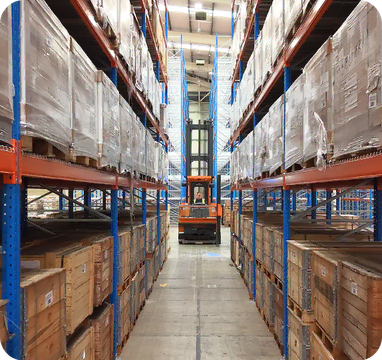 Modern VNA truck operating between high-level warehouse racking in a contract packing facility